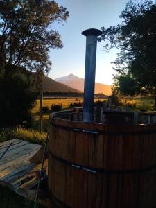 a wooden barrel with a stove in a field at Cabaña Kataleya Rio Puelo in Cochamó
