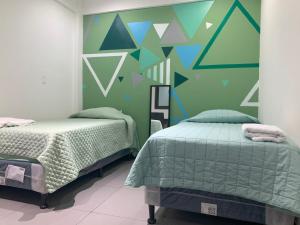 a bedroom with two beds and a green wall at Q´ojoom Jaay in San Juan La Laguna