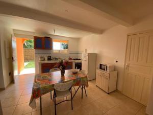 een keuken met een tafel en stoelen en een keuken met een koelkast bij La maison du plateau in Vieux-Habitants