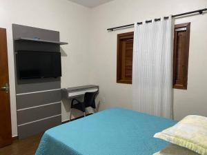 Schlafzimmer mit einem Bett, einem Schreibtisch und einem TV in der Unterkunft Casa 100 metros da praia - 3 quartos in Imbituba