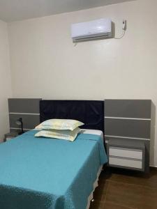 ein Schlafzimmer mit einem Bett mit einer blauen Decke in der Unterkunft Casa 100 metros da praia - 3 quartos in Imbituba