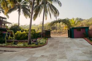 a driveway in front of a house with palm trees at Silent valley nest in Nachinola