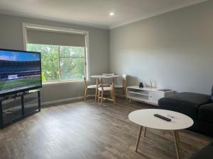 a living room with a couch and a tv and a table at 39onDewhurst in Mudgee