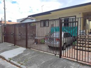 a fence with a car parked in front of a house at Hostel Sancris 2 in São José dos Campos