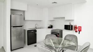 a kitchen with a glass table and chairs in it at Spectacular 2BR Apartment Full BurjAlArab View in Dubai