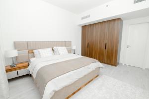 a white bedroom with a large bed and a wooden cabinet at Spectacular 2BR Apartment Full BurjAlArab View in Dubai