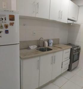 een keuken met witte kasten, een wastafel en een koelkast bij Pe na areia in Florianópolis