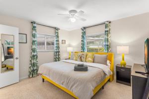 a bedroom with a yellow bed and a tv at Tropical Haven: Pool, Beach, Sun in St Petersburg