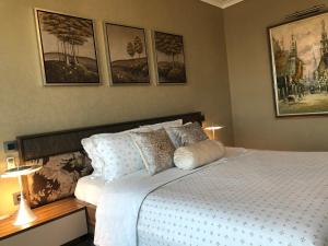1 dormitorio con 1 cama blanca con cuadros en la pared en Appart Luxe 5* de 180m² + Vue imprenable sur Oran, en Orán