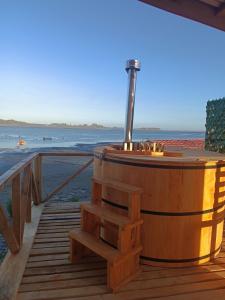 a wooden hot tub on a deck with the beach at Cabañas y Tinajas Rio Quenuir in Maullín