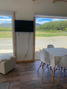 comedor con mesa, sillas y ventana en Fundo El Coigue - La Cabaña, en Cochrane