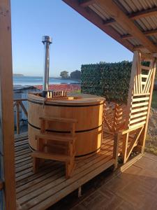 a wooden deck with a hot tub and a chair at Cabañas y Tinajas Rio Quenuir in Maullín