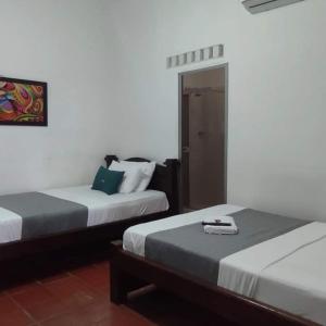 a bedroom with two beds and a door in it at Hotel Villa Ángel in Neiva