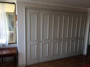 a closet with white doors in a room at Habitación Bosques de la Pirámide in Santiago