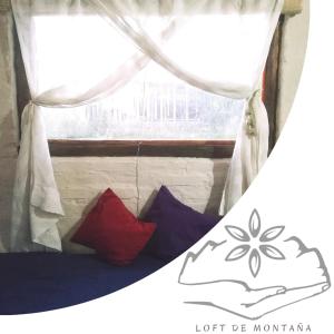 a bed with two pillows in front of a window at Vidatierra in Potrerillos