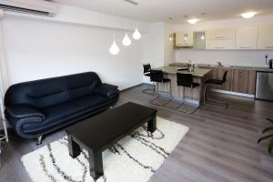 a living room with a black couch and a kitchen at Apartment Travego II in Osijek