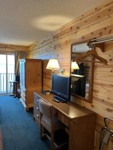 a room with a desk with a television and a mirror at Waterfront Inn Mackinaw City in Mackinaw City