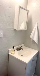 a white bathroom with a sink and a mirror at The House Hotels - Lark 1 in Lakewood