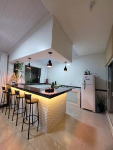a kitchen with a bar with stools and a refrigerator at Recanto Dona Fatima in Itapoa
