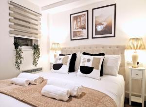 - une chambre avec un grand lit blanc et des oreillers dans l'établissement Manchester Apartments by BEVOLVE - City Centre, à Manchester