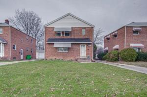 a brick house with a lawn in front of two brick buildings at Cozy Euclid Apartment Near Downtown! in Euclid