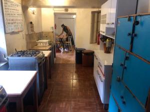 una cocina con armarios azules y una persona en el fondo en Intihuatana Hostel, en Písac