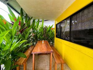 a wooden bench in front of a yellow wall with plants at Casitas Coloradas Puerto Viejo in Puerto Viejo