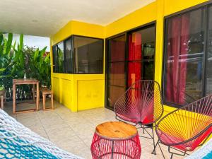 a porch with chairs and a table and a yellow building at Casitas Coloradas Puerto Viejo in Puerto Viejo
