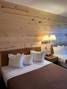a bedroom with two beds and a wooden wall at Waterfront Inn Mackinaw City in Mackinaw City