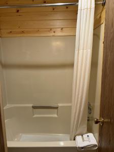 eine weiße Badewanne mit Duschvorhang im Bad in der Unterkunft Waterfront Inn Mackinaw City in Mackinaw City