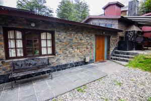 una casa de ladrillo con un banco delante de ella en Alojamiento Del Bosque en Ushuaia
