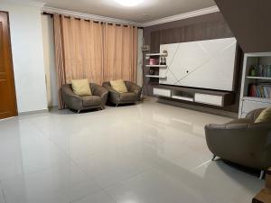 een woonkamer met 2 stoelen en een flatscreen-tv bij Sibu Homestay Happy Family in Sibu