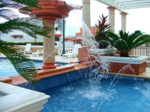 a swimming pool with a fountain in a resort at Hotel Baluarte in Veracruz