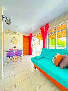 ein Wohnzimmer mit einer grünen Couch und lila Stühlen in der Unterkunft Casa de Anita Pinheira 30m da praia in Palhoça