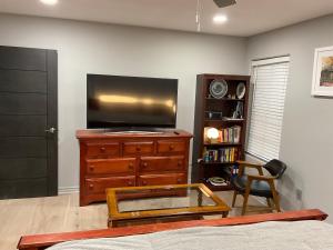 a living room with a tv on a wooden dresser at A Luxury Master Bedroom in a Condo in Los Angeles