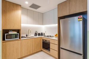 a kitchen with wooden cabinets and a stainless steel refrigerator at Kula Wollongong in Wollongong