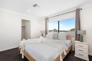 a white bedroom with a large bed and a window at Luxury Urban Retreat in Perth