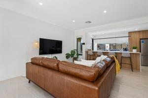 a living room with a brown leather couch and a kitchen at Luxury Urban Retreat in Perth