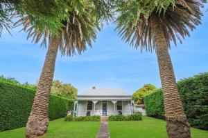two palm trees in front of a house at Palm Cottage in Port Fairy