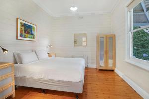 a bedroom with a white bed and a window at Palm Cottage in Port Fairy