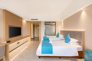 a hotel room with two beds and a flat screen tv at Shengyi Holiday Villa Hotel in Sanya