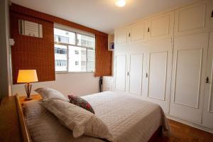 1 dormitorio con 1 cama con lámpara y ventana en Fronteira Leblon/Ipanema - Vista fantástica!, en Río de Janeiro