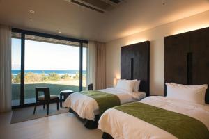 two beds in a room with a view of the ocean at Maple Beach Golf & Resort in Gangneung