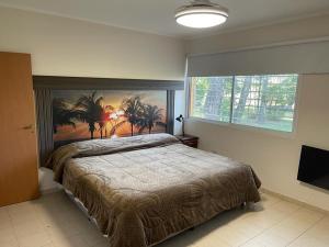 een slaapkamer met een bed met een schilderij van palmbomen bij Quinta con piscina BitcoinsHouse Los Azahares Santa Ana in Laguna Brava