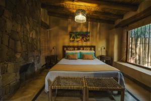 1 dormitorio con 1 cama grande y pared de piedra en Aguacanto Cabañas en Tilcara