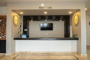 eine Lobby mit zwei Uhren an der Wand und einem TV in der Unterkunft HOTEL MERLOT INN in Ezequiel Montes
