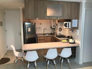 a kitchen with a counter and four white chairs at Condominio Parquemar in El Tabo