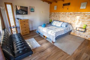 1 dormitorio con cama y sofá de cuero en Lodge Terra Mar, en Pichilemu