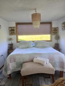 1 dormitorio con 1 cama con ventana y manta en Habitaciones Punto Medio 1, en Puerto Varas