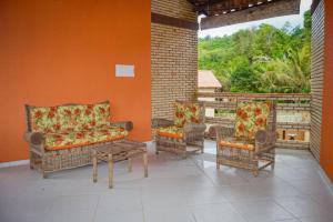 eine Terrasse mit Stühlen, einem Sofa und einem Fenster in der Unterkunft Ap Classic - Pousada Flor da Serra - Mulungu in Mulungu